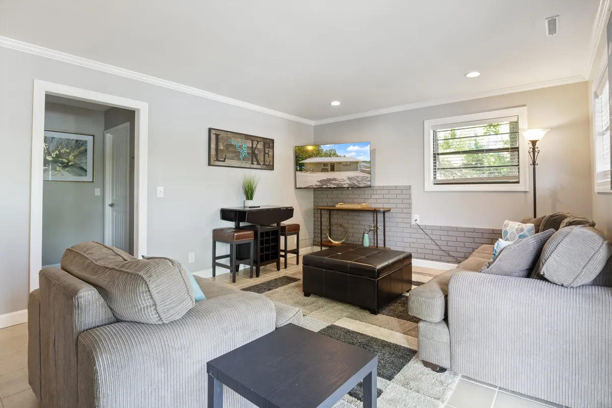 Features a welcoming living space with comfortable sofas, a coffee table, television, wall art, and a nearby dining area. The setup is perfect for socializing, movie nights, and game evenings.
