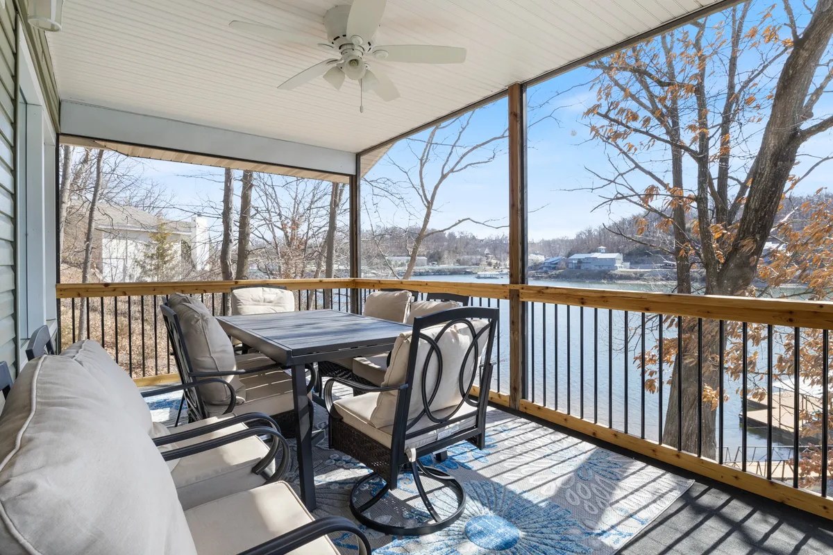 A welcoming outdoor dining area set with a table and comfortable seating, all overlooking a tranquil water view. The surrounding trees provide privacy and a natural atmosphere, while the scene is bathed in inviting sunlight, ideal for both morning coffee and sunset dinners.