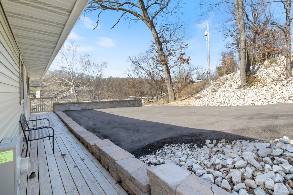 A peaceful deck area featuring rocky landscaping and surrounded by trees, with an open space that invites gathering and relaxation. The setting is tranquil and hints at opportunities for both social and quiet moments in nature.