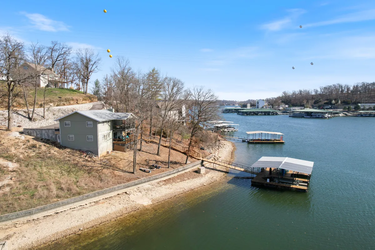 A picturesque waterfront scene showing a private boat dock and the house nestled by the shore. The tranquil water, lush greenery, and inviting dock hint at days spent boating, fishing, or simply relaxing by the lake.