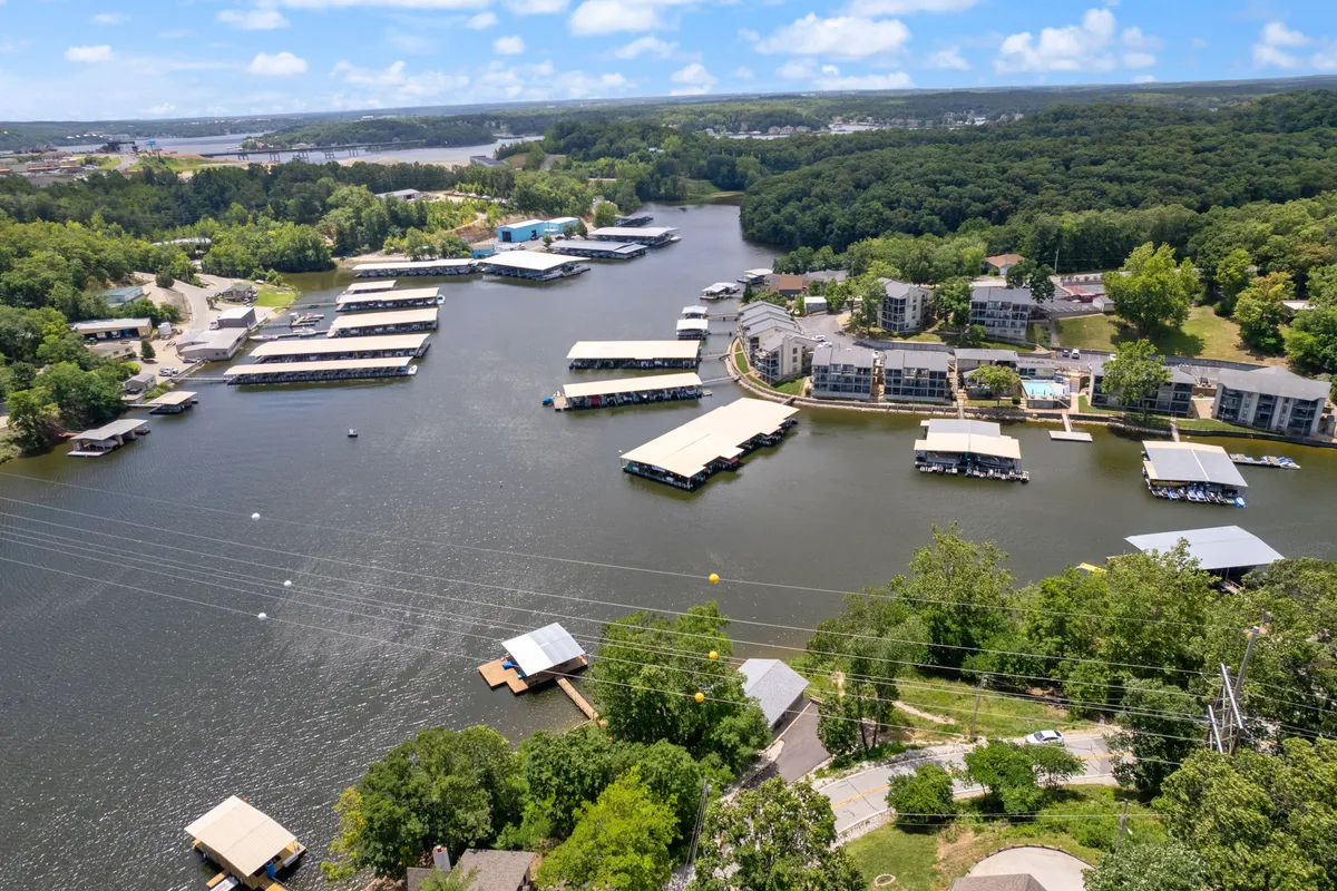 A panoramic view of lake docks set against lush greenery and residential homes. Boats are docked along the water, suggesting lively recreational activity while retaining a peaceful, laid-back mood ideal for lakeside relaxation and access to local attractions.